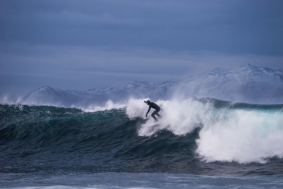 surfing norway with snowy mountains