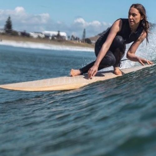 Geniya riding a wooden longboard