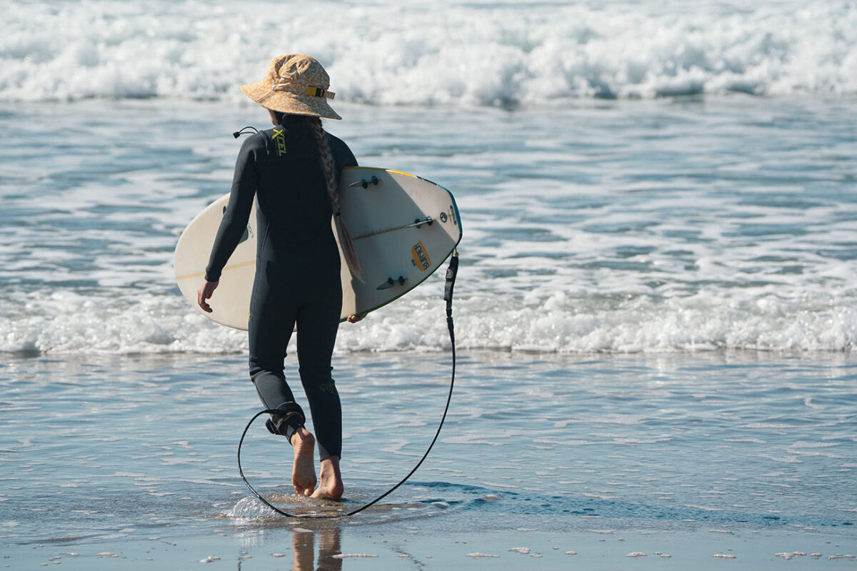 A surfer girl is wearing Xcel Comp wetsuit for kids, size 8.