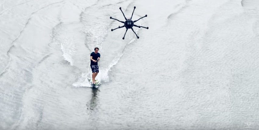 man on surfboard being towed by a drone