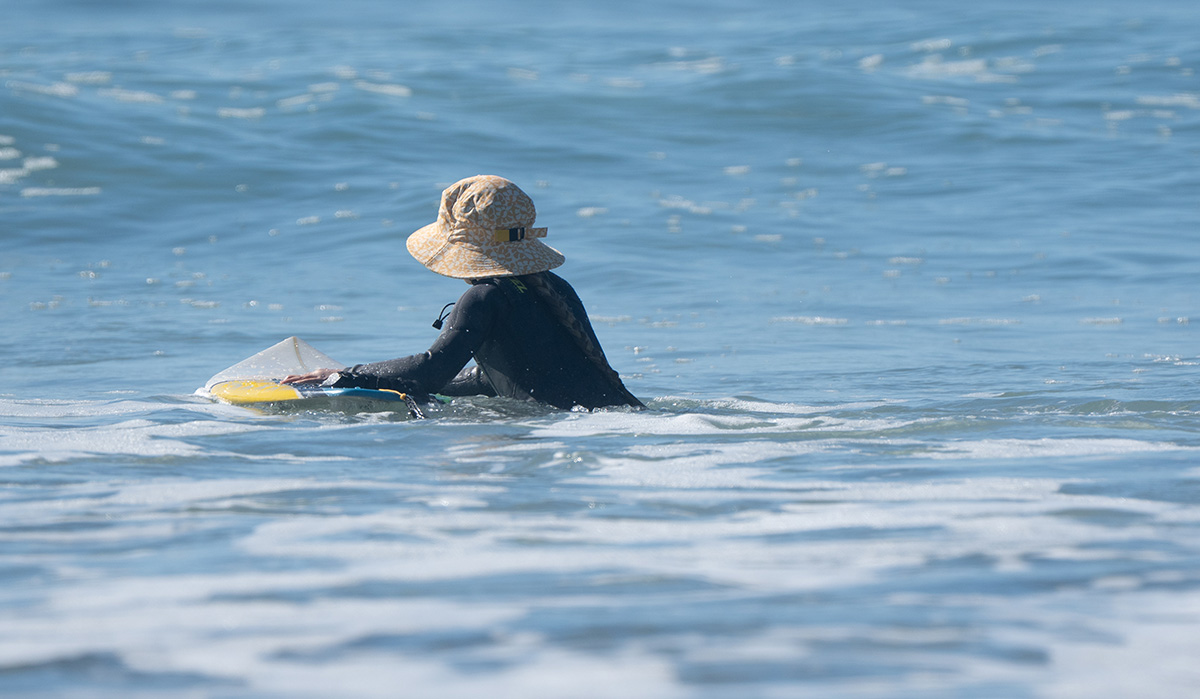 A surfer girl wearing a sun hat for surfing.
